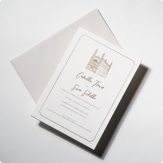 Wedding invitation card with pale gold church illustration, fine border and matching envelope on a white surface